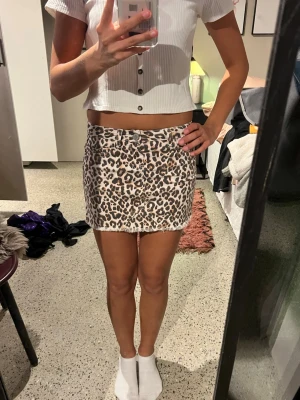 Leopardmönstrad kortkjol i bomull - Säljer en snygg kortkjol med leopardmönster i beige, brunt och svart. Kjolen har rå kant nertill och klassisk jeansmodell med fickor både fram och bak. Perfekt för dig som vill sticka ut lite extra. Skriv för frågor🩷🫶🏼