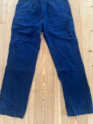 Mörkblå linnebyxor med resårmidja - Snygga mörkblå linnebyxor med avslappnad passform och resår i midjan. Byxorna har sidfickor fram och bakfickor, perfekta för en chill och stilren look. Tillverkade i lätt och luftigt linnematerial.