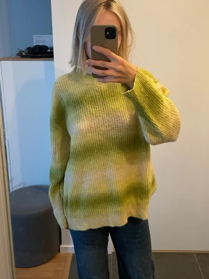 Grön och gulmelerad stickad tröja  - Säljer en oversized stickad tröja från Topshop i storlek S med gröna och gula toner med mjuk, melerad effekt. Tröjan har rund halsringning, långa ärmar och ribbade muddar vid ärmslut och nederkant. 10 kr!
