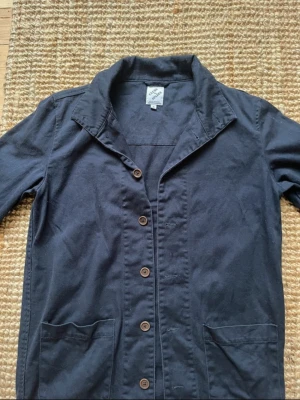 Mörkblå overshirt - Overshirt i mörkblått bomullstyg med klassisk krage, fem bruna knappar framtill och två stora fickor. Långärmad modell med normal passform som är enkel att styla till olika looks. Passar ca 175+