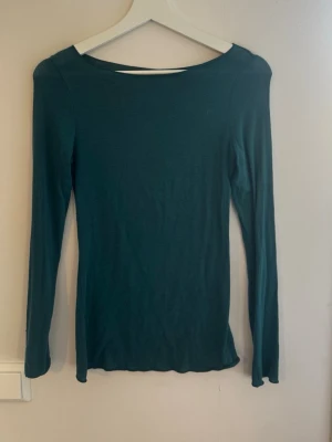 Mörkgrön Intimissimi topp - En stilren mörkgrön långärmad topp från Intimissimi med rund halsringning. Modellen är figurnära och passar perfekt till jeans eller kjol. Enkel design utan mönster eller detaljer, vilket gör den lätt att matcha med olika outfits. Pris går att diskutera💕💕