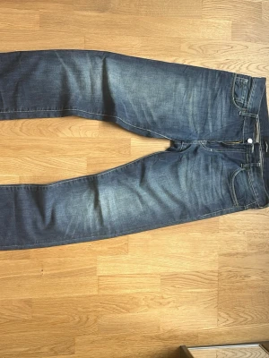 J. Lindeberg jeans mörkblå - Snygga mörkblå jeans med raka ben och diskreta slitningar framtill. Klassisk femficksmodell med kontrastsömmar och läderpatch bak i midjan.  W:31 l:34