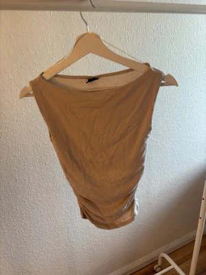 Beige ärmlös linnetopp - Snygg beige ärmlös linnetopp från Gina tricot ”soft touch boatneck top” i beige. Perfekt att styla med jeans eller den matchande kjolen för en clean look. Tunt och mjukt material som känns skönt mot huden. Rynkningar i sidorna.  Aldrig använd endast testad. Säljer även kjolen i min profil om man vill ha den till, vid köp av båda blir priset 249 kr. Nypris på tröjan 200 kr, mitt pris 99 kr. 