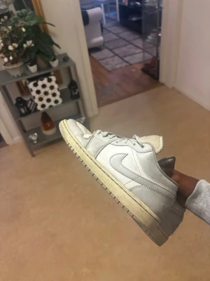 Vita låga sneakers med Swoosh - Säljer ett par vita låga sneakers med klassisk Swoosh på sidan och broderad logga på hälen. Skorna har en vit ovandel i läder och en något gulnad sula för en retro look. Perfekta för dig som gillar stilrena och tidlösa sneakers.