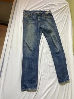 Levis blue jeans - Ett par klassiska blå jeans med raka ben och snygga slitningar. Storlek står ej på jeansen. Längd = 111cm, bredd = 44cm
