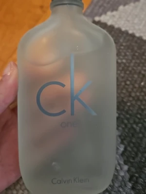 CK One parfym från Calvin Klein - Minimalistisk och stilren parfymflaska  från Calvin Klein 200ml. Knappast använd! Doften är unisex och luktar fräscht, flaskan har en enkel design som passar perfekt i badrumshyllan. Notera att den saknar lock.