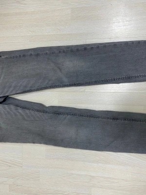 Grå slim fit jeans från Jack & Jones - Snygga grå slim fit jeans från Jack & Jones med klassisk femficksdesign och bälteshällor. Jeansen har en diskret tvättad look och är tillverkade i ett mjukt denimtyg som sitter skönt hela dagen.