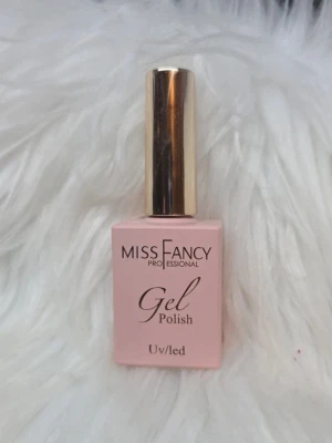 Miss Fancy Gel Polish Sheer Gloss - Miss Fancy Professional Gel Polish i färgen Sheer Gloss. Flaskan är ljusrosa med ett guldfärgat lock och har en fyrkantig form. Gelén är anpassad för UV/LED och ger en glansig finish till naglarna.
