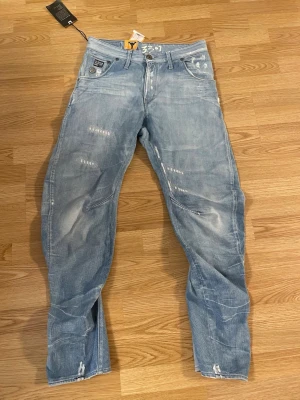 Ljusblåa G-Star RAW jeans med slitningar - Säljer ett par ljusblå jeans från G-Star RAW med coola slitningar och tvättade detaljer. Jeansen har raka ben, klassisk femficksmodell och vita tryckdetaljer vid linningen. Pris kan diskuteras !!! Storlek W34 L34