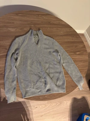 Ljusgrå stickad tröja med halv dragkedja från Zara - Snygg ljusgrå stickad tröja med halv dragkedja och ståkrage. Tröjan har lång ärm och ribbstickade muddar vid ärmslut och nederkant. Perfekt för lager-på-lager och enkel att matcha med jeans eller chinos.