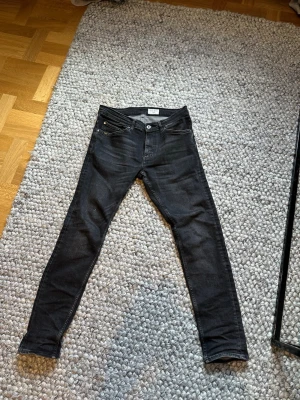 Svarta jeans från Tiger of Sweden - Säljer ett par svarta jeans från Tiger of Sweden med klassisk femficksmodell och diskreta slitningar. Jeansen har smal passform och är tillverkade i stretchigt denimtyg för extra komfort. Perfekta för en stilren och modern look nu till vår 🍃🌼 och sommar☀️⛱️.                              Enbart använda 4 gånger sen köp då de ej passar😅  Nypris på dessa ligger runt 1000 kr men mitt pris 300 kr❗️.     Har du några frågor eller funderingar är det bara att höra av sig ❗️🙌