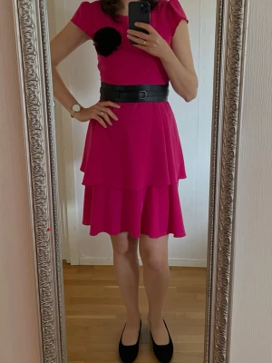 Rosa klänning stl M  - Säljer en snygg rosa klänning med korta ärmar. Klänningen har en enkel, elegant design och är tillverkad i ett mjukt, följsamt material som ger ett fint fall. Perfekt för dig som vill sticka ut med färg! Storlek M, eur 38