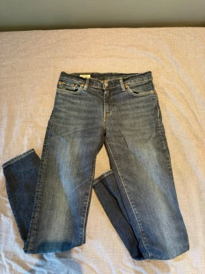 Levi's 511 - Klassiska blå jeans från Levi's med rak passform och fem fickor. Jeansen har snygga slitningar och kontrastsömmar, samt den ikoniska läderpatchen bak i midjan. Perfekta till vardags för en avslappnad look.