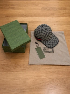 GG keps  - Snygg grå gg keps perfekt inför sommaren. Allting som är med på bilderna medföljer alltså box, dustbag och taggen till den. Den är storlek M (58cm) och justerbar där bak. Den är aldrig använd och den är i nytt perfekt skick. Kom med frågor ifall ni har några! (Pris går att diskuteras vid snabbaffär)
