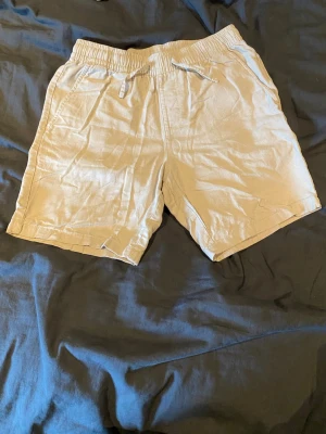 Beige shorts med snörning från 157 - Snygga beige shorts från 157 med elastisk midja och snörning. Tillverkade i ett lätt och luftigt material, perfekta för varma dagar. Shortsen har sidofickor och en avslappnad passform som ger en chill vibe.