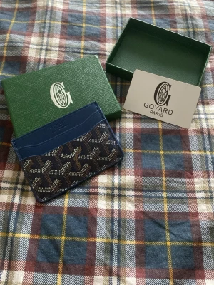 Blå riktigt stilig korthållare  - Snygg blå korthållare från med klassiskt mönster i vitt och brunt. Tillverkad i läder och canvas, perfekt för kort och ID. Kommer med originalask. Stilren och lyxig accessoar för dig som gillar exklusiva detaljer.