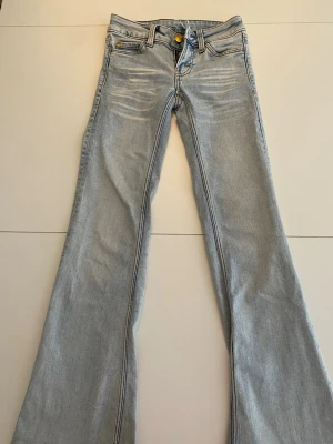 Ljusblå bootcut jeans med grönt märke - Säljer ett par ljusblå bootcut jeans med klassiska fickor från Cheap monday och är i storlek 23/30!