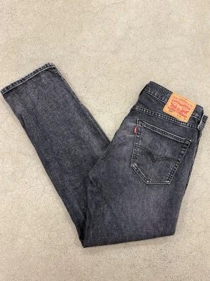 Levi's 559 svarta / gråa jeans - Säljer ett par svarta Levi's 559 jeans med rak passform och klassisk femficksdesign. Jeansen har en snygg tvättad look, Levi's patch bak och röd logotagg vid bakfickan. Perfekta för dig som gillar en avslappnad stil. Storlek W32 L32.