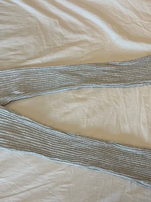 Grå ribbade leggings från H&M - Säljer ett par gråmelerade leggings från H&M med ribbad struktur och smala ränder. De har elastisk midja och är tillverkade i ett mjukt och stretchigt material.