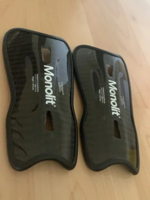 Monolit benskydd i kolfiber - Säljer ett par svarta benskydd från Monolit i kolfiber med ergonomisk form och mjuk vadderad insida. Lätta och smidiga skydd som ger bra täckning för smalbenen. Perfekta för dig som vill ha extra skydd vid träning eller match. 