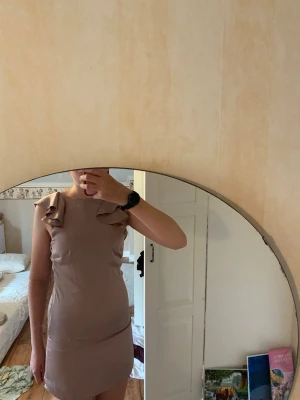 Lila kort klänning med volang - Snygg lila kort klänning med volangdetaljer på axlarna och öppen rygg. Klänningen har en figurnära passform, finns ingen lapp men skulle säga att den är i storlek S. Materialet är i ett silkesliknande tyg så den är väldigt skön och lätt att ha på sig.