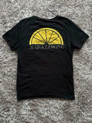 Acqua Limone t-shirt - Säljer en svart t-shirt från Acqua Limone med klassisk på ryggen. T-shirten har rund hals och är gjord i mjuk bomull. Perfekt för dig som gillar stilrena och ikoniska plagg.