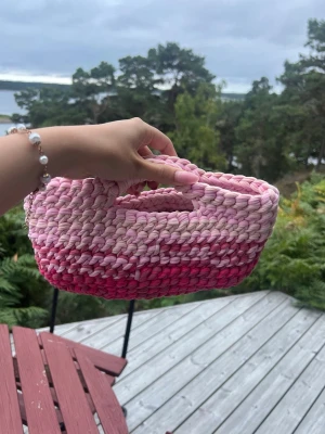 Handvirkad rosa  väska - Söt handvirkad väska i olika nyanser av rosa. Väskan har en rektangulär form med integrerade handtag. Perfekt för småprylar eller som accessoar till din outfit.💕💕