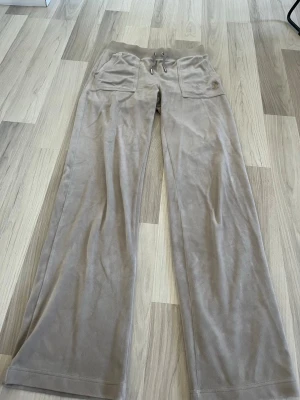 Juicy couture byxor  - Beiga juicy couture byxor i storlek xs. Använts en del, har inga defekter förutom på J märket på fickan. Säljer även gråa!  Postar mellan 1-3 dagar efter köp.  Hör gärna av dig om du har frågor eller vill ha fler bilder!