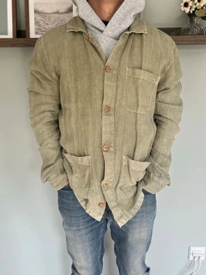 Morris Ethan L Shirt Jacket Beige/Khaki M - Morris Ethan L Shirt Jacket i beige/khaki med stilren och klassisk design. Skjortjacka med knappstängning fram, bröstficka och två större fickor nedtill. Perfekt över en t-shirt eller hoodie och passar enkelt med jeans eller chinos.  Skick: fint skick, inga hål eller fläckar Storlek: M / 39–40 Modell: 175 cm / 65 kg — sitter true to size på bild
