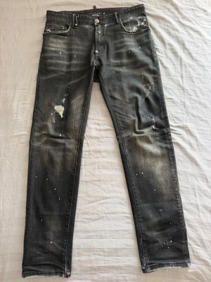 Philipp Plein jeans  - Säljer ett par unika svarta slim fit jeans i strl 34, från Philipp Plein med slitningar, färgstänk och råa detaljer. Jeansen har fem fickor, unika nitar i grönt, vitt och rött vid fickan samt en snygg tvättad look. Perfekta för dig som gillar ha en unik och fräsch look. Fraktar inom 24h efter köp. Hör av dig vid frågor! 