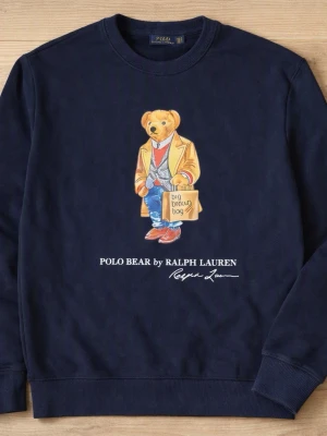 Mörkblå sweatshirt Polo Bear Ralph Lauren - Mörkblå sweatshirt från Ralph Lauren med ikoniska Polo Bear-trycket framtill. Rund halsringning, ribbade muddar och avslut. Mjuk bomullskvalitet och avslappnad passform. Perfekt för en casual och trendig look.