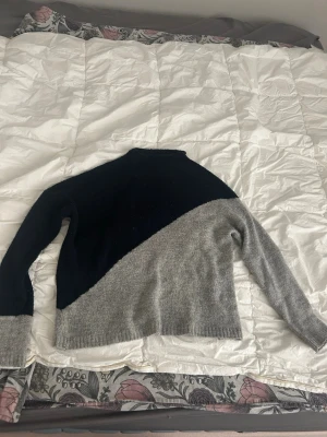 Tvåfärgad stickad tröja - Säljer en snygg stickad långärmad tröja i svart och grått med en diagonal. Perfekt fören enkel men stilren look, speciellt till hösten💕