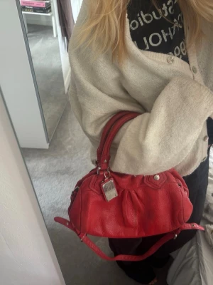 Vintage Marc Jacobs väska - Vintage Marc by Marc Jacobs väska i modellen Q Classic Baby Groove. Rött läder med silvriga detaljer. Långt band som går att ta av. Måtten är ungefär 33x18x12.   Väl använd och tecken på slitage men ingenting som är sönder eller trasigt. Svart märke på baksidan (se bild 8-9).   Perfekt till både vardags och fest😌  Pris diskuteras vid snabbt köp 🩷🩷🩷