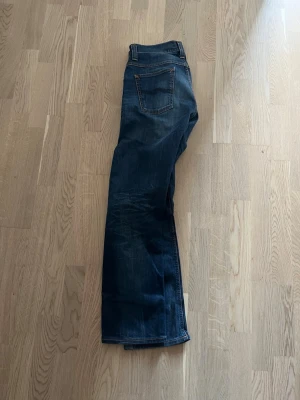 Mörkblå Nudie jeans - Säljer ett par Nudie jeans med relaxed bootcut som sitter sjukt snyggt! Storlek 30/32