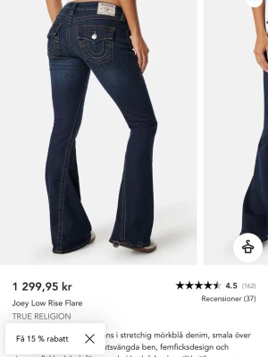 True Religion mörkblå flare jeans - Snygga flare jeans från True Religion i stretchig mörkblå denim. Modellen har låg midja, smala lår och utställda ben. Klassisk femficksdesign och kontrastsömmar. Perfekta för dig som gillar retrovibbar och vill sticka ut.