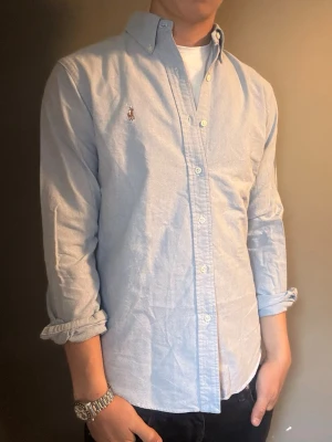 Ralph Lauren skjorta Ljusblå – M slim fit -  Säljer denna stilrena och snygga ljusblåa Ralph Lauren skjortan. Skjortan är i mycket bra skick och storlek M slim fit. Perfekt för både vardag och mer uppklädda tillfällen. Har du några frågor? Tveka inte att höra av dig. Allt gott från Deluxe Garderoben ⭐️