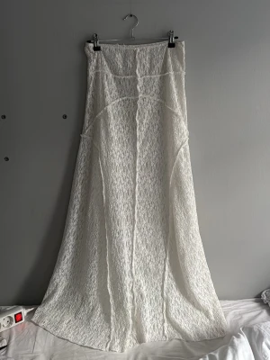 Vit långkjol i spets - Säljer en elegant vit långkjol med vacker spets och lätt utsvängd passform. Kjolen har fina sömdetaljer och ger en romantisk vibe. Perfekt för dig som vill ha en feminin och stilren look.