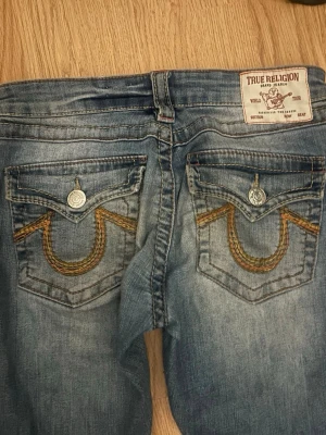 Lowrise True Religon Bootcut  - Lowrise Bootcut jeans från True Religon i modellen Joey. Snygga och trendiga och bra skick. Obs, små slitningar längst ner och lite på fickorna.