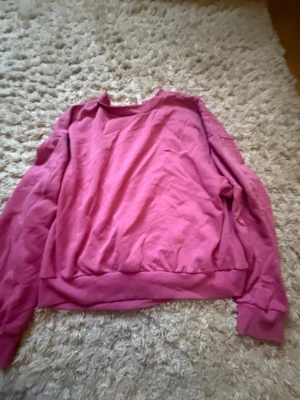 Rosa sweatshirt med rund hals - En enkel och snygg rosa sweatshirt med rund hals och långa ärmar. Tröjan har ribbade muddar vid ärmslut och nederkant. Perfekt för en avslappnad och trendig look.