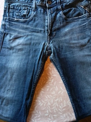 Blå jeans från Replay - Säljer ett par klassiska blå jeans från Replay med snygg tvätt och fem fickor. Jeansen har normal midja, raka ben och slitna detaljer för en avslappnad look. Tillverkade i bomull med en skön passform. Perfekta till din vardagsstil!