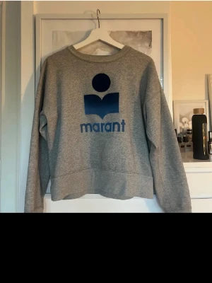 Grå sweatshirt från Marant - Säljer en grå sweatshirt från Isabel Marant med blå logga och text framtill. Säljer pga att den inte kommer till användning längre!