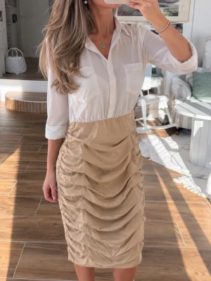 Beige & vit skjortklänning med draperad kjol – B.P.C. Bonprix stl 36 - Vit och beige skjortklänning från b.p.c. med klassisk skjortkrage, knappar framtill och trekvartsärm. Kjoldelen är beige med snygga rynkade detaljer och figurnära passform. Perfekt för dig som gillar stilrena och moderna plagg.