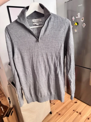Halfzip - Snygg och stilren grå stickad tröja från Autograph i extra fin merinoull. Tröjan har lång ärm, hög krage och halv dragkedja framtill. Perfekt för dig som gillar en clean och klassisk look med premiumkänsla.