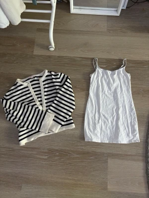 Randig svartvit stickad tröja och ett vitt linne - OBS !! Linnet på sista bilden är inte samma som det vita på den andra. Säljer en snygg stickad tröja med svarta och vita horisontella ränder. Tröjan har långa ärmar. Använd en gång, helt ren inga hål, långt vitt linne utan lapp. Linne storlek S tror jag, kofta: xs original pris 299 & ca 149?