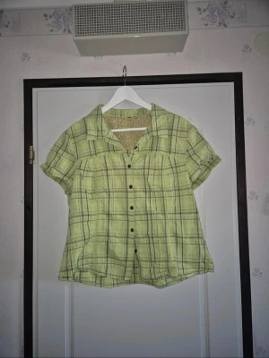 Grön rutig skjorta 100% bomull - Söt ljusgrön kortärmad blus med rutigt mönster, knappar framtill och fina spetsdetaljer. Perfekt för en somrig outfit eller för dig som gillar cottagecore, vintage och Y2K-stilen. I fint skick, vad jag kunnat se några större defekter.