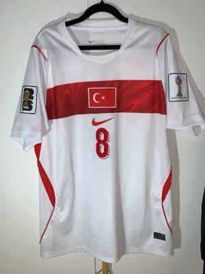 L. Äkta turkiet 2026/2027 2nd kit - Har använt max 5 gånger totalt 10 timmar Jag är en fotbolls tröja samlare i över 15år nu väljer jag och sälja den pågrund av min ps5 gick sönder för 2 dagar sen behöver köpa en ny därför väljer jag sälja den här en av några fotbolls tröjorVit fotbollströja från Nike med röd rand och Turkiets flagga på bröstet. Nummer 8 och Arda Güler på ryggen. FIFA och turneringsmärken på ärmarna. Perfekt för dig som vill stötta Turkiets landslag.