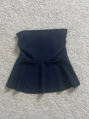 Marinblå tub topp från  Missäy - Snygg marinblå bandeau topp från Missäy med utsvängd peplum-nederdel. Toppen är axelbandslös och har en stilren, enkel design som passar perfekt till många olika looks. Använd en gång. Passar xs/s. Skriv vid intresse💞priset går att diskutera 