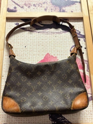 Louis Vuitton Boulogne 30 Monogram - Klassisk Louis Vuitton vintageväska med mycket karaktär och fin patina. Väskan är väl använd från tidigare ägare och har naturligt slitage som passar den äldre modellen och ger en unik vintagekänsla. När jag köpte väskan var fästet där den guldfärgade ringen till axelremmen sitter redan slitet och förstärkt. Det fungerar fortfarande bra, men se bilder för skick. I övrigt är väskan i okej vintage-skick och har många år kvar att användas. Äkthetsintyg från Vintage Luxuries medföljer.