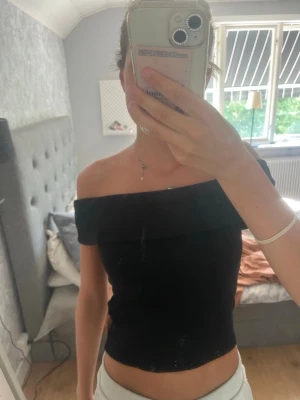 Svart offshoulder topp Gina Tricot - Säljer en svart offshoulder topp från Gina Tricot i mjukt material. Toppen är tight och har en axelbandslös design som sitter snyggt över axlarna. Använd någon gång bara