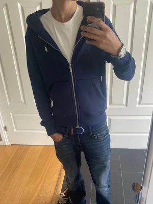 Ralph Lauren Hoodie - Snygg marinblå zip hoodie från Ralph Lauren. Storlek S och passar om man är ca 170-176 cm. Riktigt bra skick som ny! Om du har frågor eller funderingar är det bara att höra av dig! MVH Lucas🥂